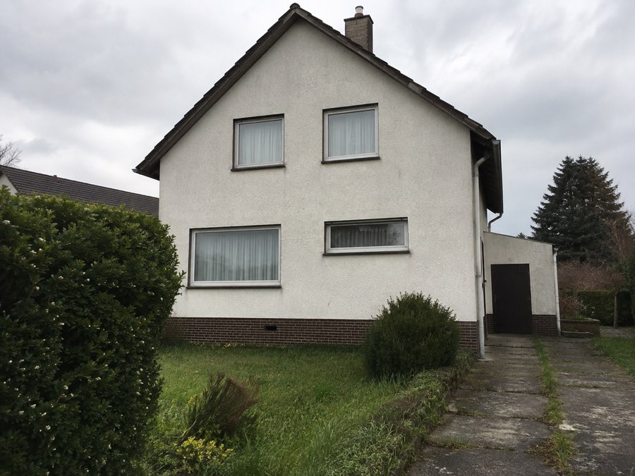 Freistehendes Einfamilienhaus mit hellem Putz und dunklem Klinkersockel